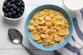 Bowl of tasty corn flakes and blueberries served for breakfast on white wooden table, flat lay Royalty Free Stock Photo