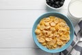 Bowl of tasty corn flakes and blueberries served on white wooden table. Space for text Royalty Free Stock Photo