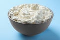 Bowl of tasty cream cheese on light blue background, closeup Royalty Free Stock Photo