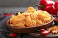 Bowl with tasty crispy potato chips on wooden board Royalty Free Stock Photo