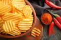 Bowl with tasty crispy potato chips on wooden board, closeup Royalty Free Stock Photo