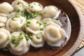 Bowl of tasty dumplings in broth on table Royalty Free Stock Photo