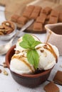 Bowl of tasty ice cream with caramel sauce, mint, nuts and candies on white table, closeup Royalty Free Stock Photo