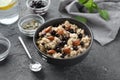 Bowl with tasty oatmeal, berries and nuts on grey textured background