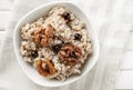 Bowl with tasty oatmeal, berries and nuts on white table