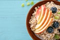 Bowl with tasty oatmeal, fruit and berries on wooden table