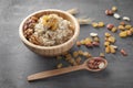 Bowl with tasty oatmeal, raisins and nuts on grey background