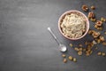 Bowl with tasty oatmeal, raisins and walnuts on grey background