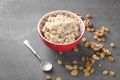 Bowl with tasty oatmeal, raisins and walnuts on grey background