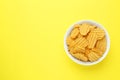 Bowl of tasty ridged potato chips on yellow background, top view. Space for text Royalty Free Stock Photo