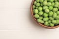 Bowl with tasty wasabi coated peanuts on white wooden table, top view. Space for text Royalty Free Stock Photo