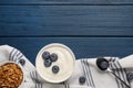 Bowl of tasty yogurt served with blueberries and muesli on blue wooden table, flat lay. Space for text Royalty Free Stock Photo