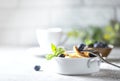 Bowl with tiny pancake cereal on a light concrete background. Trendy food. Mini cereal pancakes with butter, honey and blueberries