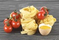 Bowl of tomato sauce, cherry tomatoes, egg and italian pasta on wooden background. Royalty Free Stock Photo