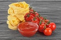 Bowl of tomato sauce, cherry tomatoes and italian pasta on wooden background Royalty Free Stock Photo