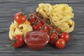 Bowl of tomato sauce, cherry tomatoes and italian pasta on wooden background Royalty Free Stock Photo