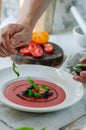 Bowl of tomato soup with basil on white background. Cold pink tomato soup. Restaurant supply.