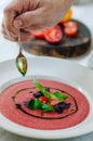 Bowl of tomato soup with basil on white background. Cold pink tomato soup. Restaurant supply.