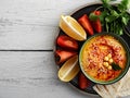 Bowl with traditional homemade hummus with olive oil and fresh vegetables. Slices of lemon and pita nearby on a plate. Useful Royalty Free Stock Photo