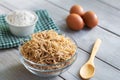 Bowl of traditional Turkish noodle raw with eggs and spoon on wooden background