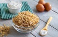 Bowl of traditional Turkish noodle raw with eggs and spoon on wooden background