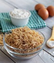 Bowl of traditional Turkish noodle raw with eggs and spoon on wooden background