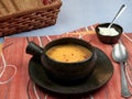 A bowl of tripe soup Romanian: Ciorba de Burta set on a red napkin placed on a blue tablecloth, served with extra cream and a ba