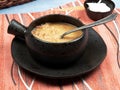 A bowl of tripe soup Romanian: Ciorba de Burta set on a red napkin placed on a blue tablecloth, served with extra cream and a ba