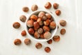 Bowl with unpeeled hazelnuts on white wooden background