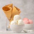 Bowl of vanilla and pink berries ice cream and waffle cones on light background. Side view Royalty Free Stock Photo