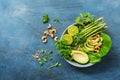 A bowl with a variety of herbs, avocados, asparagus, micro greens, lime and cashews. Detox bowl buddha. Blue rustic background, to
