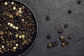 Bowl of various pepper peppercorns seeds mix on dark background.