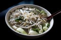 a bowl of Vietnamese pho, seen here with Thai basil and bean sprouts on top of the broth. a spoon is inserted on the side Royalty Free Stock Photo
