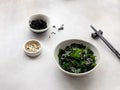 Bowl with wakame seaweed with chopsticks and sesame seeds on gray background Royalty Free Stock Photo