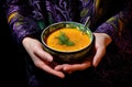 Bowl of warm pumpkin soup in hands. Holding bowl of vegan pumpkin soup.