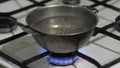 Water is boiling in a metal pot. Bowl of water warmed on a dirty old gas stove at home, close up. Poverty destitution