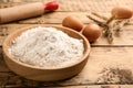 Bowl with wheat flour near eggs and spikelets on wooden table. Space for text Royalty Free Stock Photo