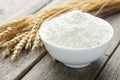 Bowl of wheat flour with spikelets on grey wooden background Royalty Free Stock Photo