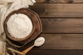 Bowl with wheat flour, spoon and spikelets on wooden table, flat lay