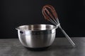 Bowl and whisk with chocolate cream on grey table against black background Royalty Free Stock Photo