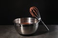 Bowl and whisk with chocolate cream on table against black background Royalty Free Stock Photo