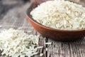 A bowl of white rice against the background of old boards near sprinkled rice. Jasmine rice for cooking Royalty Free Stock Photo