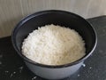 A bowl of white rice is on the black tabl