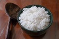 A bowl of white rice and a wooden ladle on a brown wooden table Royalty Free Stock Photo