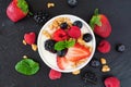 Bowl of yogurt with healthy fresh berries and granola, close up top view on a dark stone background Royalty Free Stock Photo