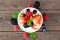 Bowl of yogurt with healthy fresh berries and granola, close up top view over rustic wood Royalty Free Stock Photo
