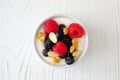 Bowl of yogurt with healthy fresh berries and granola, close up top view on white wood Royalty Free Stock Photo