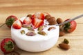 Bowl of yogurt, red fruit strawberry and dried fruit on the wood table. Yogurt made from milk fermented by added bacteria, often Royalty Free Stock Photo