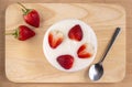 Bowl of yogurt and red fruit strawberry on the wood table. Yogurt made from milk fermented by added bacteria, often sweetened and Royalty Free Stock Photo