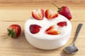 Bowl of yogurt and red fruit strawberry on the wood table. Yogurt made from milk fermented by added bacteria, often sweetened and Royalty Free Stock Photo